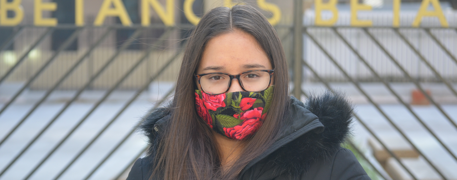 A girl with glasses and a flower mask looking at the camera