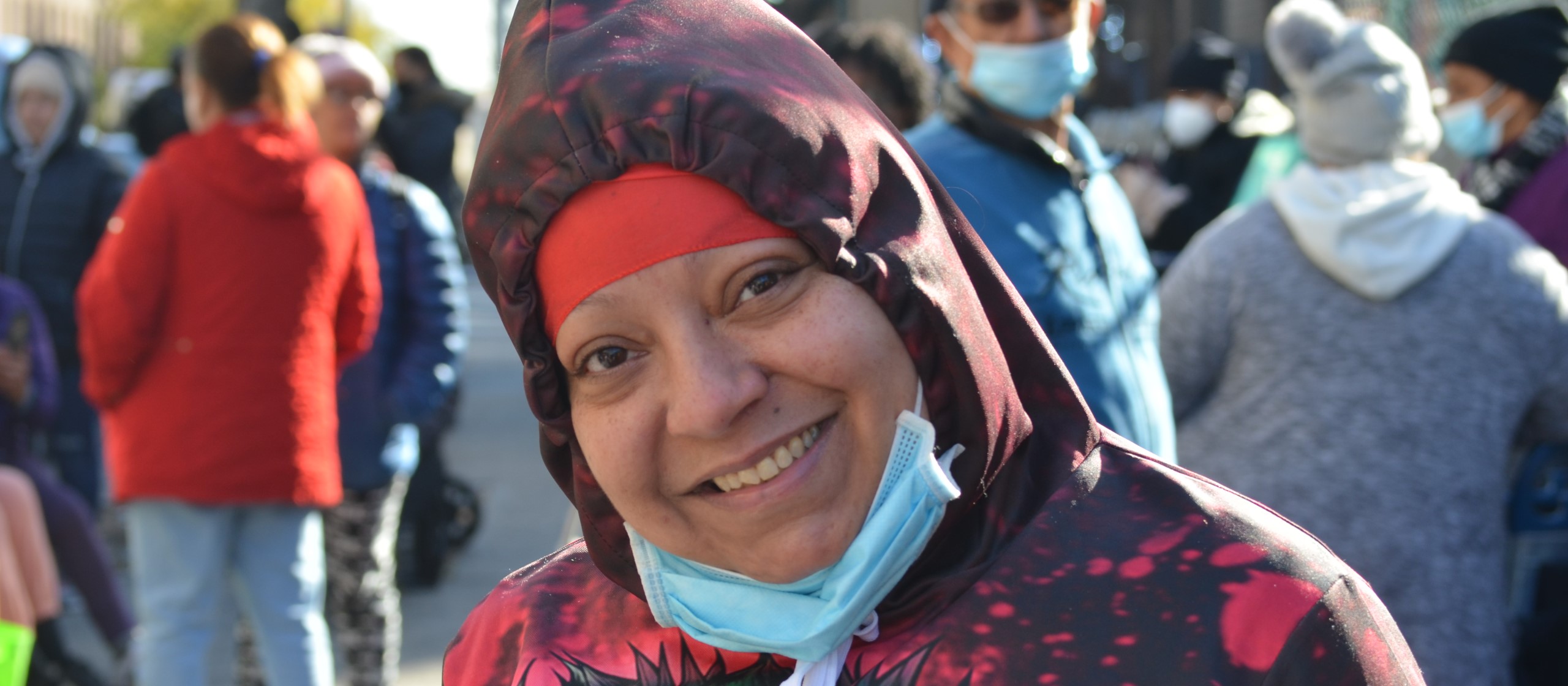 A woman with a mask around her chin smiles at the camera.