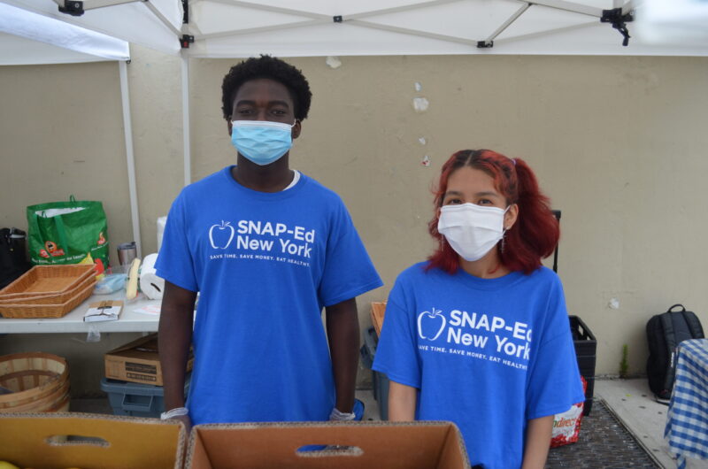 Two SYEP participants wearing SNAP Ed t-shirts stand at Farm Stand