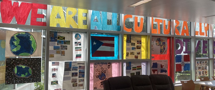 A window is plastered with handmade posters describing different parts of the world. A large banner at the top reads "We Are All Culturally Diverse".