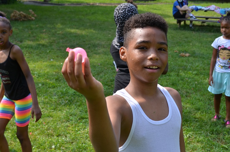A young boy shows off his water balloon.