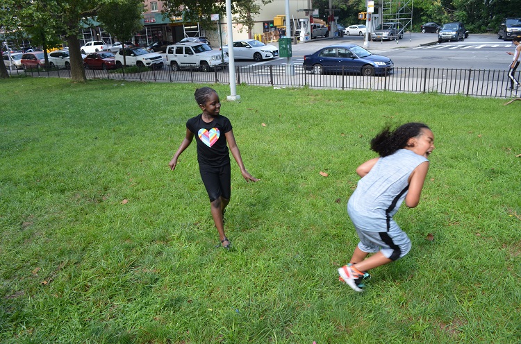 A girl stands to the side just having thrown a water balloon at another student on the right who is laughing.