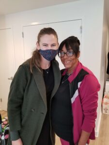 Two women stand inside a new apartment, smiling.