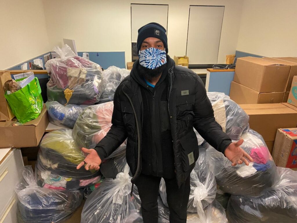 Laurence Marsach AKA @OvertimeLarry stands at BronxWorks with bags of coats and socks he and his team collected.