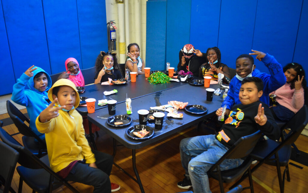 Children sitting around a table enjoying pizza, water bottles, and juice boxes.