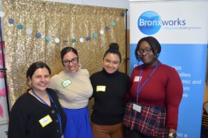 Four peopl estand in front of a gold backdrop and a BronxWorks sign