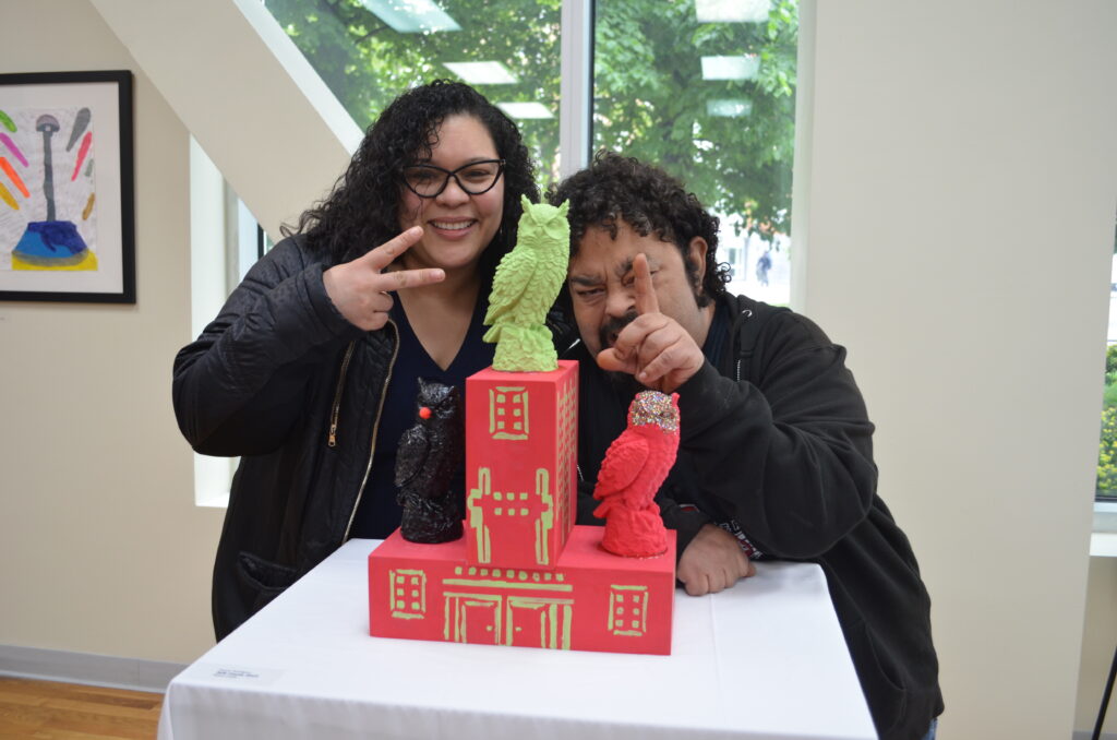 Barbara Miliano, BronxWorks Program Director at The Brook Supportive Housing and BronxWorks Supportive Housing resident Manny R. posing with his sculpture, “Safe House”