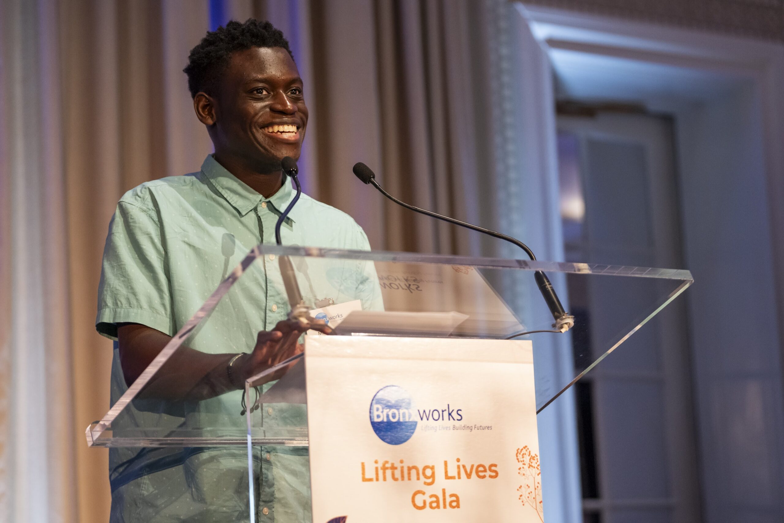 Matthew Henry speaks at a podium at the BronxWorks 2024 Lifting Lives Gala. He is smiling.