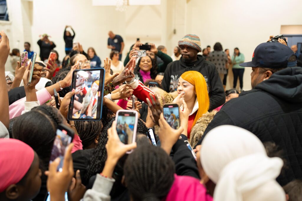 A woman waves at and greets girls excitedly waving and taking pictures