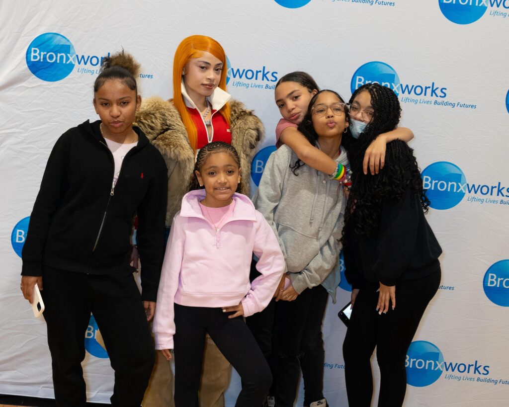 Many people stand in front of a BronxWorks Step & Repeat