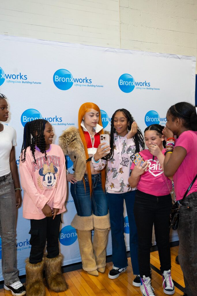 Many people stand in front of a BronxWorks Step & Repeat