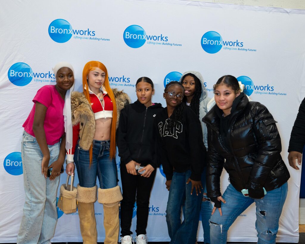 Many people stand in front of a BronxWorks Step & Repeat