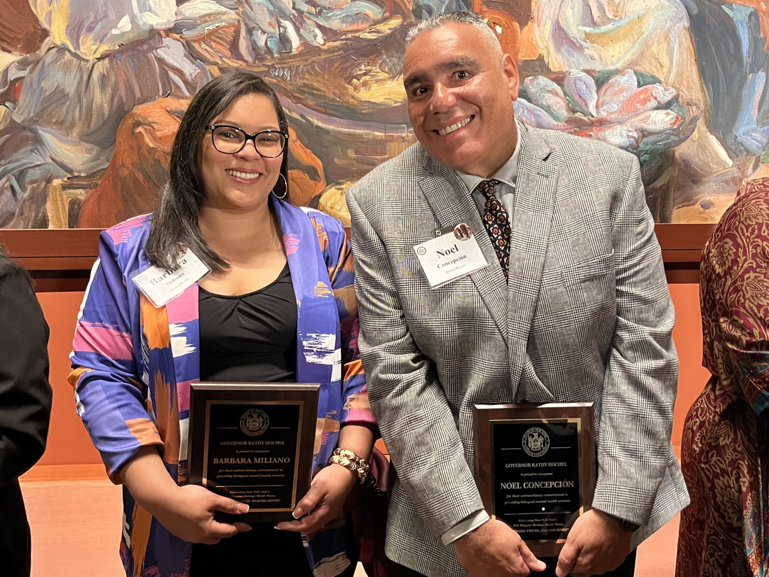 A woman and a man stand next to each other holding plaques.