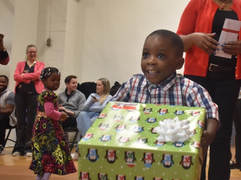 A child holding a present. A text block says "Donate New Gifts Today!"